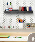 Four Pack Magnetic Spray Can Holders For Garage And Home Workshop Grab And Go Wall Mounted Tool Organizer With Open Access Design To Hold Paint Cans Oils Cleaners And Aerosol Cans on white pegboard wall, holding various spray cans and bottles, surrounded by organized art supplies.