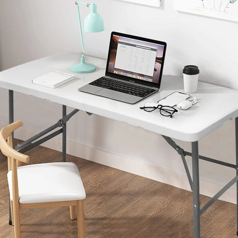 Heavy Duty 4 Foot Folding Table For Indoor Outdoor Use With Handle Portable Square Dining Card Table Waterproof Durable Plastic Top 330 Lb Weight Capacity Ideal For Picnics Parties Camping And More with laptop, lamp, books, and cup on top in home office setting
