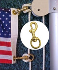 Top Shelf Heavy Duty Brass Flag Clips 4 Pack Swivel Snap Hooks For Rope Flagpole Attachment Built Tough Round Grommet compatible hooks attached to a flag.