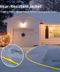 Heavy Duty 25 Foot 12 Gauge Outdoor Extension Cord With Lighted End in use, visible in snow near a house, waterproof yellow cable.