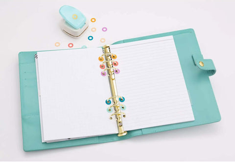 Planner with decorative hole reinforcers punch for planners and tags, adhesive circle hole punch tool in use, multi-color circles, open planner