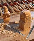 Dual Head Hammerless Nail Setter And 3/16 In Center Punch with carved wooden figures and tools on a workbench