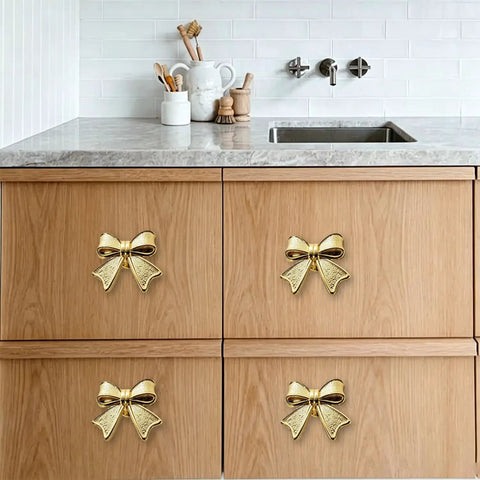 Six Piece Zinc Alloy Bow Drawer Knobs With Vintage Plating And Smooth Curved Handles For Dressers And Vanity Furniture Upgrades That Bring Main Character Energy To Your Space on wooden cabinets under countertop.
