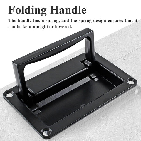 Black folding handle with spring mechanism, shown upright on a gray surface, used for recessed lift pull design