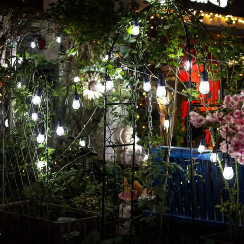 Garden setting with 30-Foot Cool White LED Outdoor String Lights With 10 Hanging Sockets, Waterproof Festoon Lighting, creating ambiance.