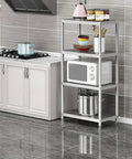 Stainless steel kitchen shelving unit with microwave and cookware, next to modern cabinets in tiled kitchen.
