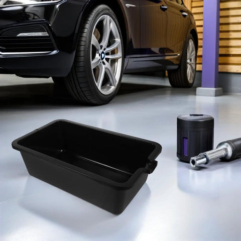 Rugged Auto Oil Drain Pan 6 Liter Plastic Basin for Engine Fluids Leak Cleanup with ergonomic handle beside car.