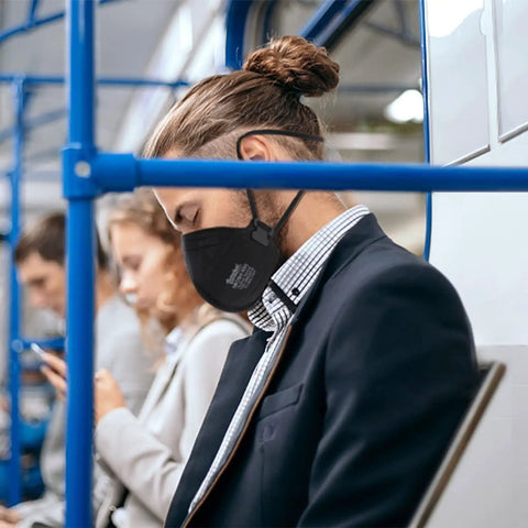 Person wearing NIOSH Approved N95 Mask Respirator Pack Of 50 Individually Wrapped Black Face Masks with Four Layer Filtration on public transport