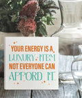 Your Energy Is a Luxury Inspirational Quote Wood Box Sign Desk Decor against vase and glass backdrop