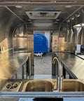 Interior view of Rock Solid Heavy Duty Mobile Coffee Concession Cart With Spacious Storage Compartments, featuring stainless steel sink and counter.