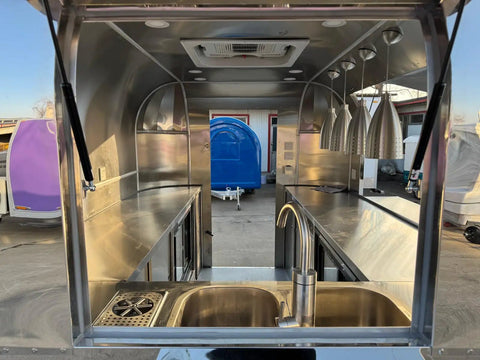 Interior view of Rock Solid Heavy Duty Mobile Coffee Concession Cart With Spacious Storage Compartments, featuring stainless steel sink and counter.