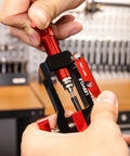 Close-up of hands using 3 In 1 Hydraulic Brake Tool For Bikes Hose Cutter Needle Driver And 7 8mm Brake Line Wrench in workshop