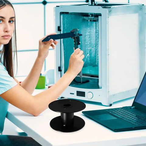 Super Slick Empty Cable Winder Reel 165mm Plastic Cord Organizer on table while a woman uses caliper near a 3D printer.