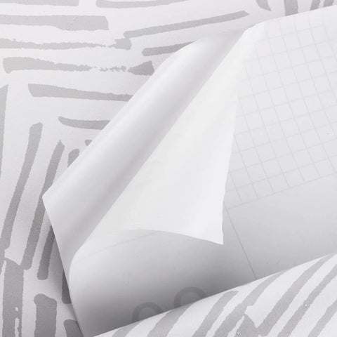 Close-up of striped peel and stick wall paper grey and white vinyl self adhesive contact paper partially peeled back