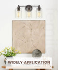 Three Light Vanity Light Fixture For Farmhouse Bathroom With Metal Wall Sconce Clear Glass Shades Oil Rubbed Bronze Finish E26 Base Socket LED Compatible Incandescent Friendly Durable Rustic Modern Look above a textured art piece.