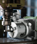Rotary table for milling machines with a 3-jaw chuck, gray metal body and calibrated dial scale.