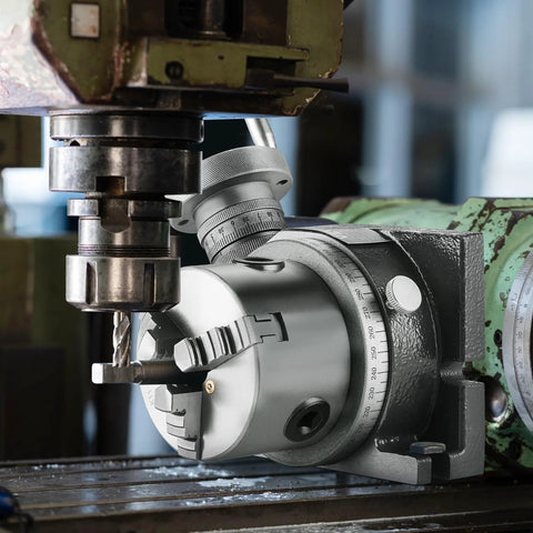Rotary table for milling machines with a 3-jaw chuck, gray metal body and calibrated dial scale.