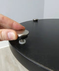 Close-up of Beat The Wobble Instantly 1 1/4 Inch Round Floor Protectors being installed on a table.