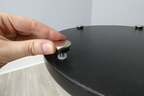 Close-up of Beat The Wobble Instantly 1 1/4 Inch Round Floor Protectors being installed on a table.
