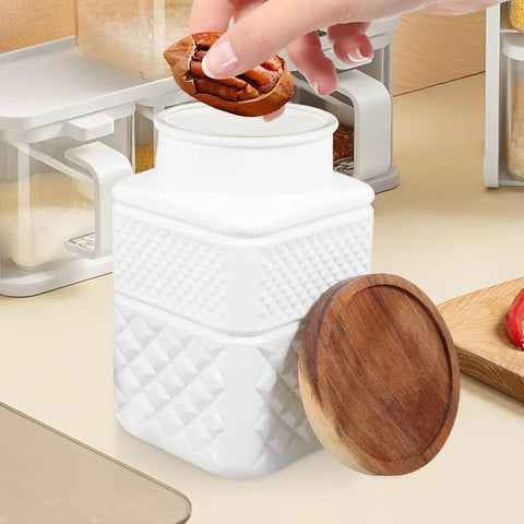 Hand placing a snack into Sweet Matte White Glass Jars With Smooth Bamboo Lids Rock Solid Airtight Food Storage Containers For Kitchen Coffee Beans Cereal And Spices Organization 1800Milliliter Two Piece Bundle.