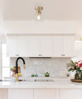 Harrow 1 Light Semi Flush Mount Ceiling Light In Matte Brass With Clear Glass Shade in a modern kitchen setting.