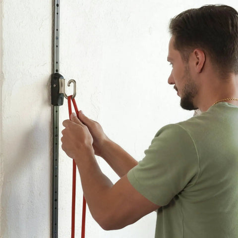 User attaching red resistance bands to Space Saving Wall Mount Gym Anchor System for workouts.
