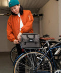 Person attaching 4 In 1 Dayliner Box Bag 20 Liter Water Resistant Rolltop to bike rack in garage.