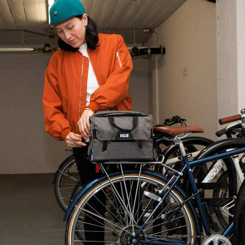 Person attaching 4 In 1 Dayliner Box Bag 20 Liter Water Resistant Rolltop to bike rack in garage.