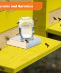 Two Pack Light Wood Beehive Entrance Feeders with bees drinking from jar placed on yellow hive platform.