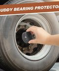 Hand installing a gray 1.98 inch rubber trailer bearing dust cap on a wheel hub for protection against dirt and moisture.