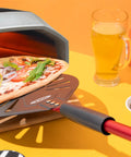 TKC 9-inch perforated aluminum pizza peel with long red handle and TKC logo.
