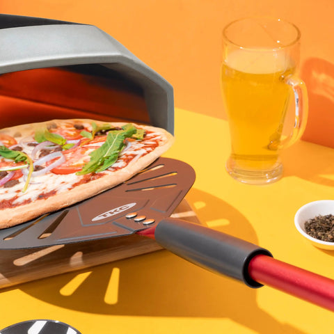 TKC 9-inch perforated aluminum pizza peel with long red handle and TKC logo.