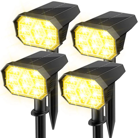 Four warm yellow solar pathway lights standing upright with stakes, shown illuminated, waterproof design visible.
