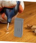 Gloved hand using tool with Floor And Tile Repair Wax Kit For Porcelain And Ceramic Tiles Quick Drying Hard Wax Filler on wood surface