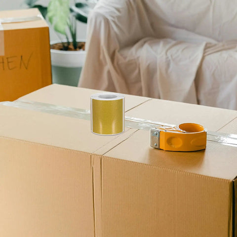 Golden Thermal Label Paper for shipping and mailing on cardboard box with tape dispenser nearby, ideal for office printers.