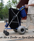 Person pushing Beach Cart With Balloon Wheels, Heavy Duty Steel Wagon That Rolls Smoothly Over Sand on a paved path.