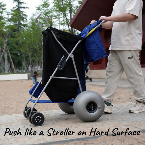 Person pushing Beach Cart With Balloon Wheels, Heavy Duty Steel Wagon That Rolls Smoothly Over Sand on a paved path.