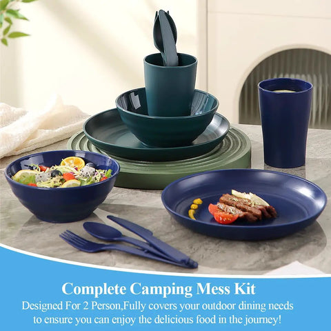 Camping Mess Kit For Two with plates, bowls, cups, utensils, dark green plastic camping essentials for outdoor meals on a table.