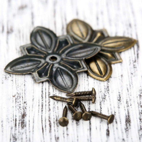 Close-up of 50 Pack Vintage Upholstery Nails Heavy Duty Iron Decorative Tacks showing antique brass finish and flower-shaped decorative tacks.