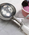 Thumb-Press Food Disher Ice Cream Scoop 4.67 Oz Size 6 White, 18/8 Stainless Steel, Commercial-Grade Portioner beside ice cream bowl.
