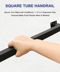 Hand gripping a matte black square tube handrail from the Kickass 7 Ft Indoor Stair Railing with non-slip grip.