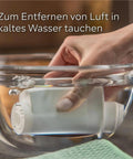 Hand submerging a Top Shelf Six Pack Replacement Water Filter Cartridge in cold water for limescale removal.