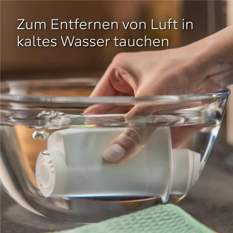 Hand submerging a Top Shelf Six Pack Replacement Water Filter Cartridge in cold water for limescale removal.