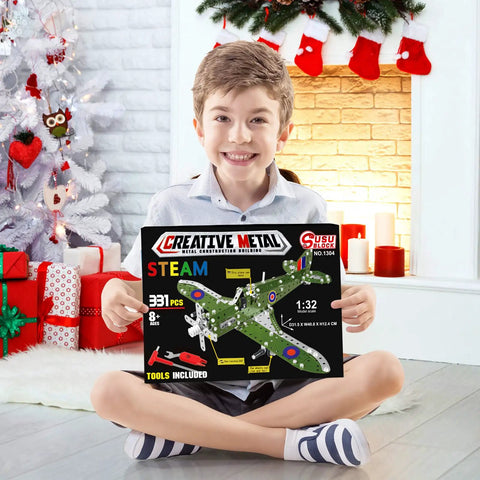 Child holding box of Build Your Own Hurricane Fighter Plane Kit With 331 Metal Parts In 1:32 Scale, seated by festive decor.