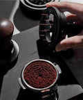 Top Shelf 58Mm Needle Distributor And Wdt Espresso Tool above finely ground coffee, showcasing stainless steel ground prep kit for espresso.