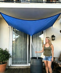 Effortless Rainwater Catcher System with hose 3 pack setup on balcony, tarp directing water to storage barrel, woman standing nearby
