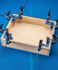 Clamp It Mini Assembly Squares 4 Pack For 90 Degree Corner Clamps In Woodworking holding a wooden box with bar clamps on blue mat