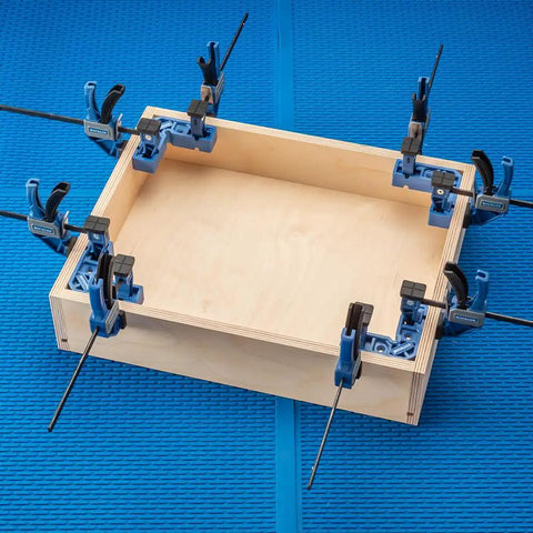 Clamp It Mini Assembly Squares 4 Pack For 90 Degree Corner Clamps In Woodworking holding a wooden box with bar clamps on blue mat
