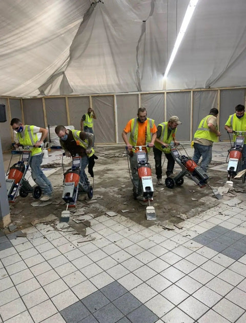 Workers using jackhammer trolley for fast demolition and tile removal in large indoor job site