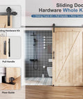 8 Foot Sliding Barn Door Hardware Track Kit With Black Wall Mount And Handle Big Industrial Spoke Wheel Pulley Smooth Quiet Glide Easy Install 96 Inch Track Fits 44 To 46 Inch Openings No Door Included installed on a wooden door with black handle and floor guide in a modern bathroom setting.